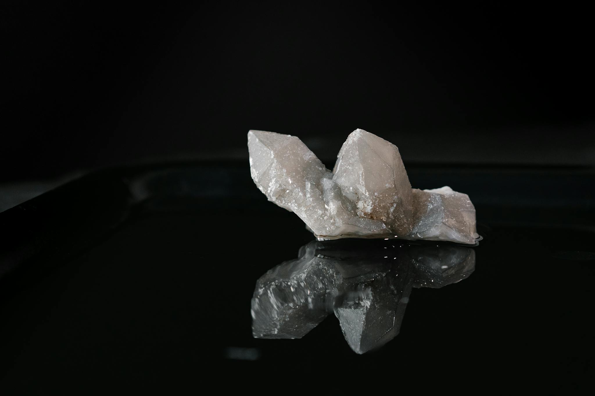 A striking quartz crystal displayed on a glossy black surface, highlighting its natural beauty and mystique.