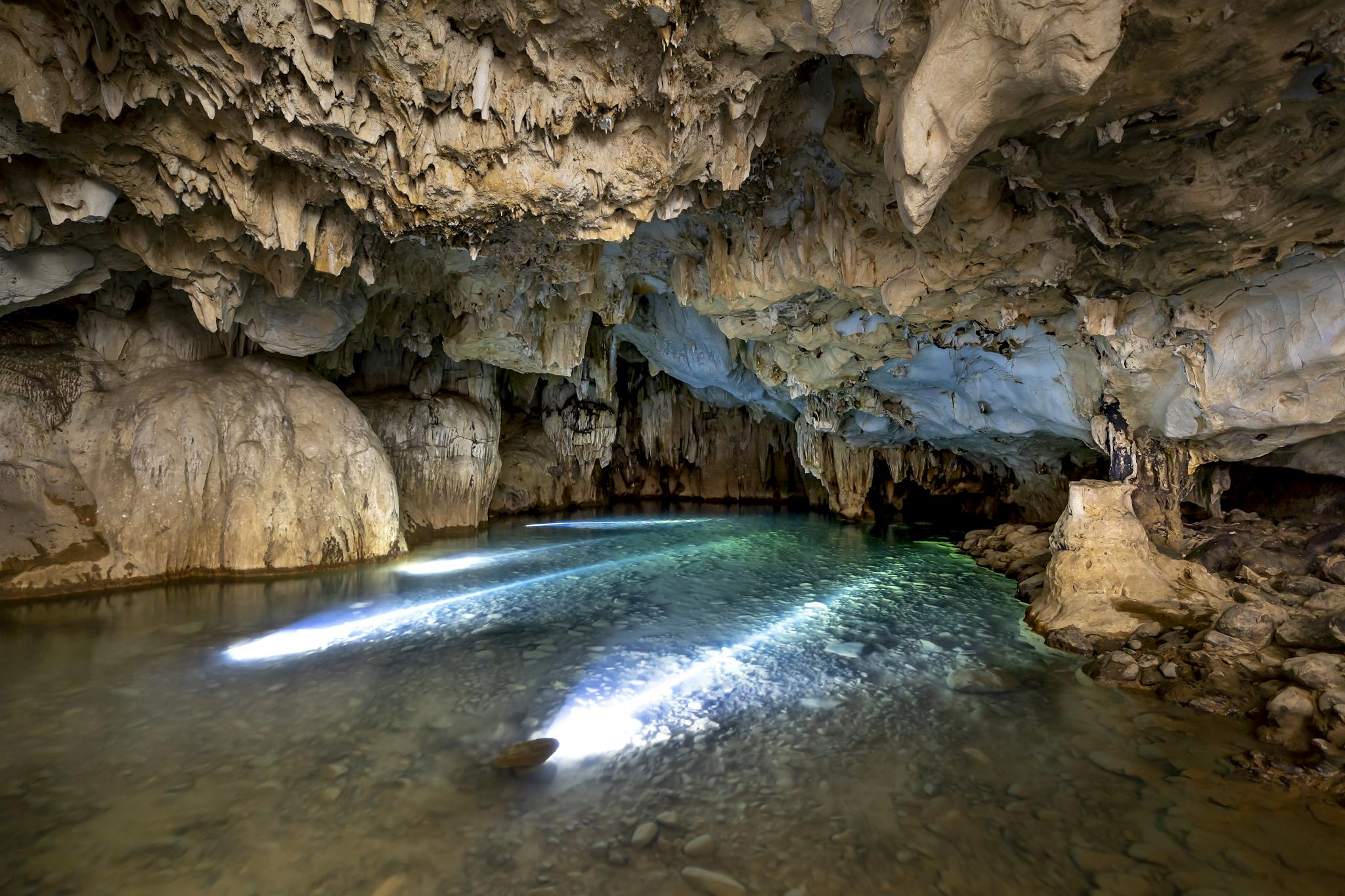 Breathtaking view of a naturally eroded cave with a tranquil lake illuminated by natural light.